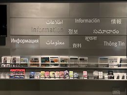 a wall that says "information" in many languages, brochures at the base of the wall