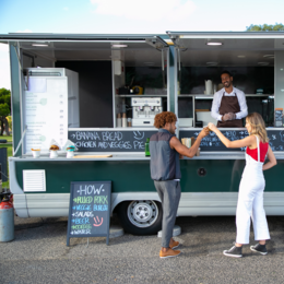 Image of a white woman and mixed black and white man getting food from a mobile food truck. 