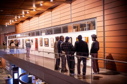 People stand on the City Hall 2nd floor catwalk looking at artworks.