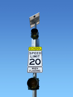 A school zone speed limit sign. It has a posted limit of 20 miles per hour when the lights on the sign are flashing.