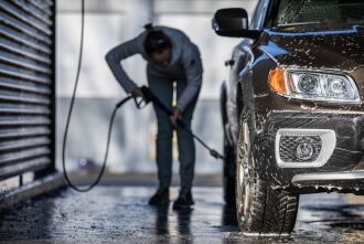 Inage of a person washing their car in a bay at a commercial car wash which is recommended by the City of Bellevue to prevent soap from polluting local creeks and lakes.
