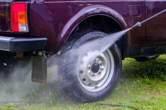 Image of a maroon-colored truck being washed on a lawn. If washing a vehicle at home, wash on a lawn or gravel area so dirty soapy wash water soaks into the ground and doesn't enter the street or storm drains. Even biodegradable soaps only degrade in soil. 
