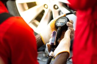 Image of tire shop staff checking the tire pressure on a car tire with a pressure gauge. 