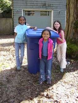 Children standing by recycle cart