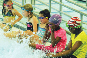 five children sitting on the edge of a pool