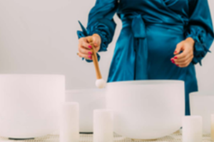 image of person with several white singing bowls on a table