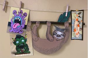 image of art wall with drawings of a sloth,  koi fish, and monsters attached to a line with clothespins