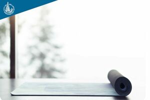 An image of a yoga mat on a floor in front of a well-lit window. 