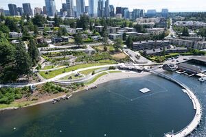 Aerial view of Meydenbauer Bay Park showing a large, curved pier, grassy areas, paths, and the historic Whaling Building and Marina.