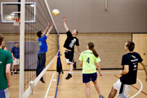 two teams playing volleyball at an indoor court