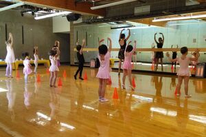 Group of toddlers in a ballet class copying instructor's pose