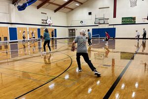 multiple groups of people playing pickleball at an indoor court