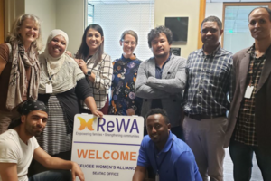 Group of people smiling at camera and standing around a welcome sign