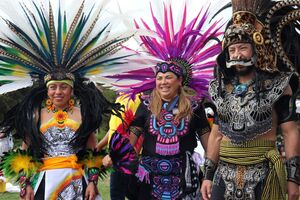 three people, wearing traditional Aztec ceremonial clothing