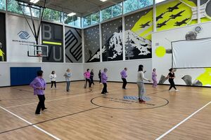 A group of people in a gym in various tai chi poses