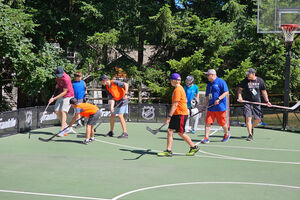 a group of boys playing hockey on a field outside