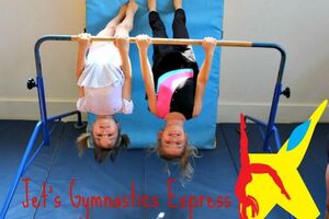 two children hang upside down on a gynmastics bar